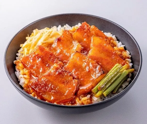 ご飯の上に、豚肉の煮込みと、ネギのような野菜が乗った料理